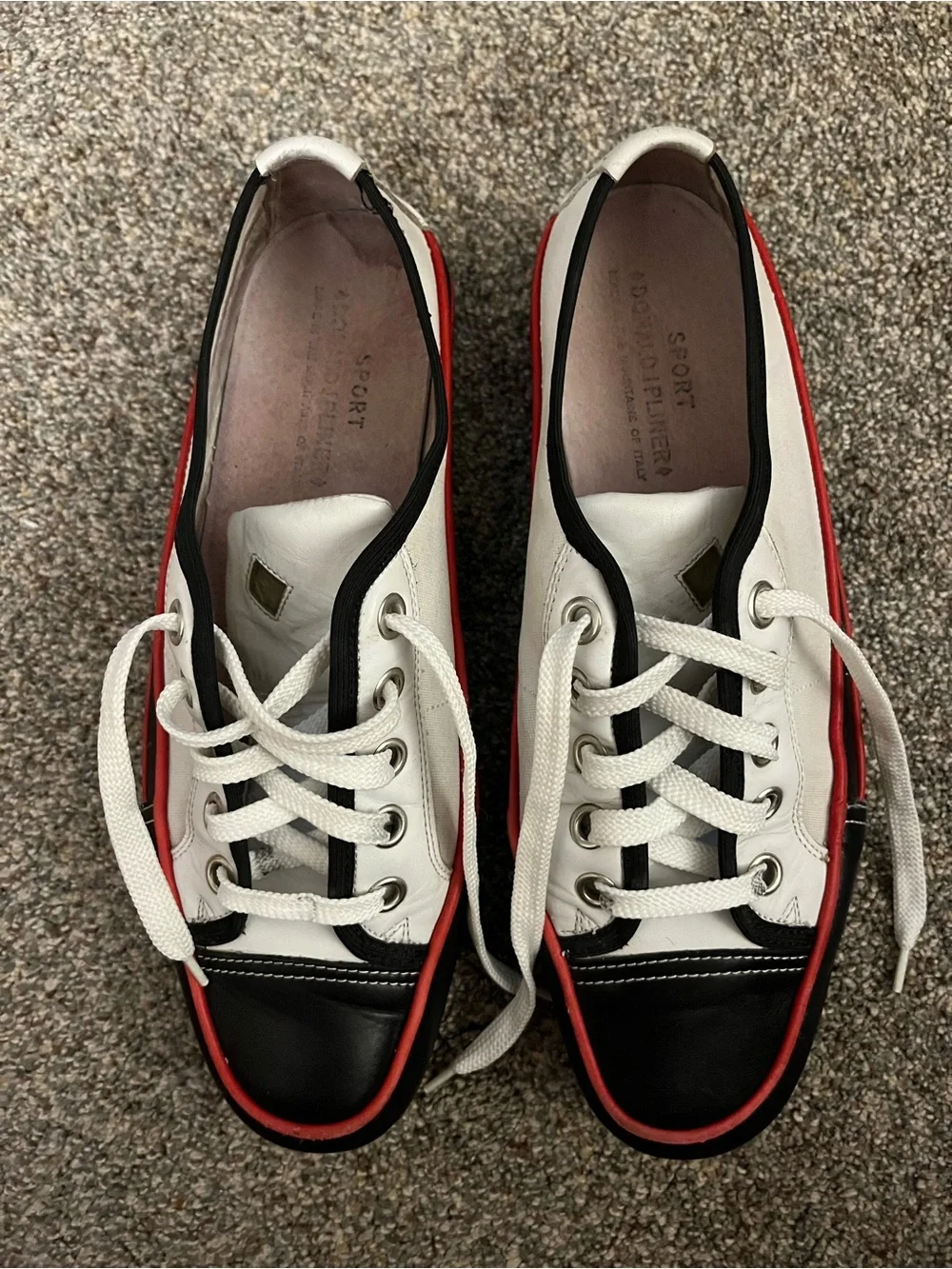 Donald J Pliner white canvas and black leather sneakers with red trim.